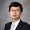 Tianshu Feng in a black suit, light-blue tie and dark glasses for his faculty profile at George Mason University.